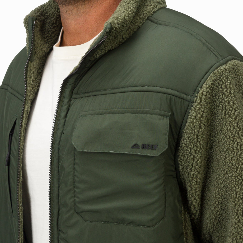 Close-up of the upper front and shoulder of Cooke Sherpa Jacket in olive green with soft, textured fabric and quilted detailing.