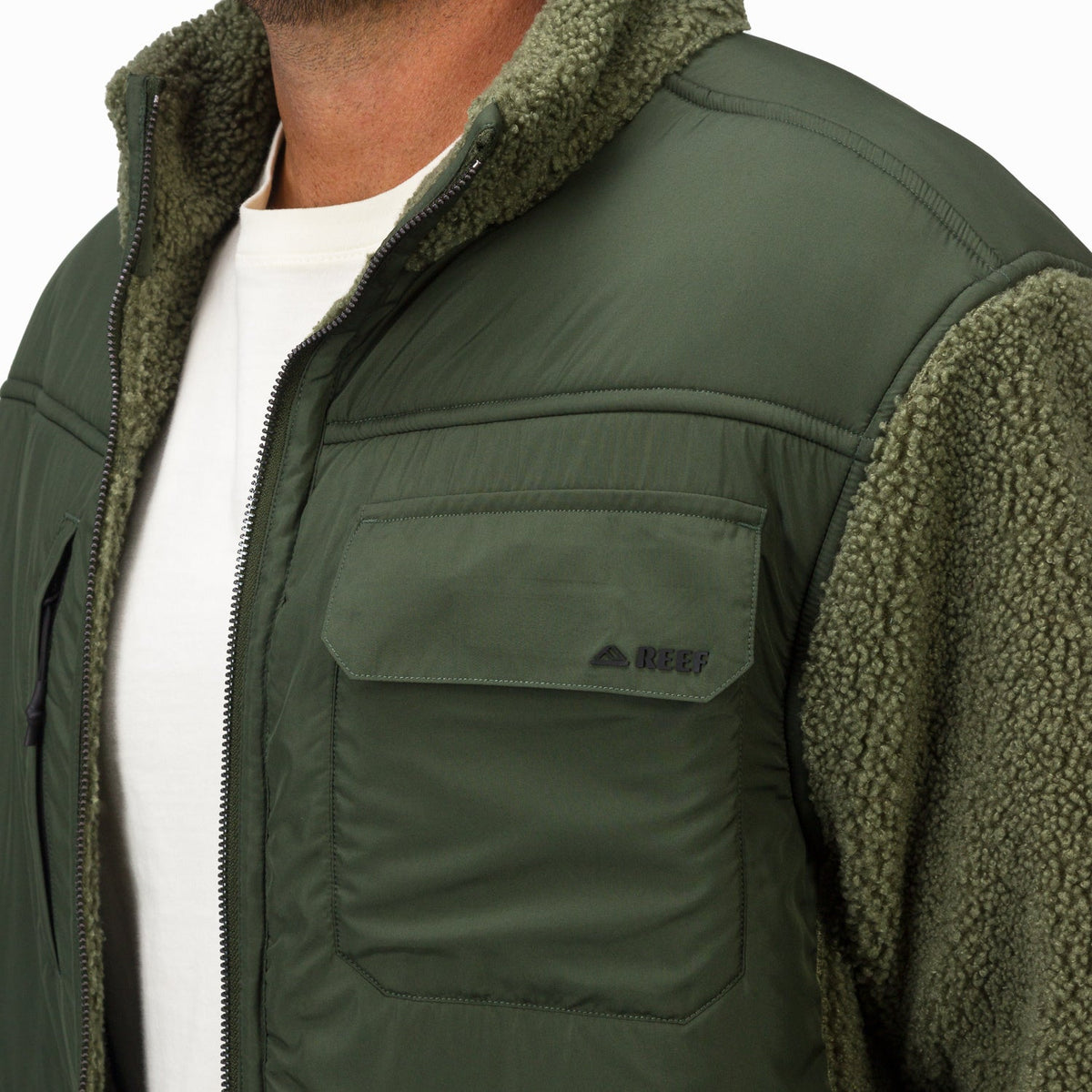 Close-up of the upper front and shoulder of Cooke Sherpa Jacket in olive green with soft, textured fabric and quilted detailing.