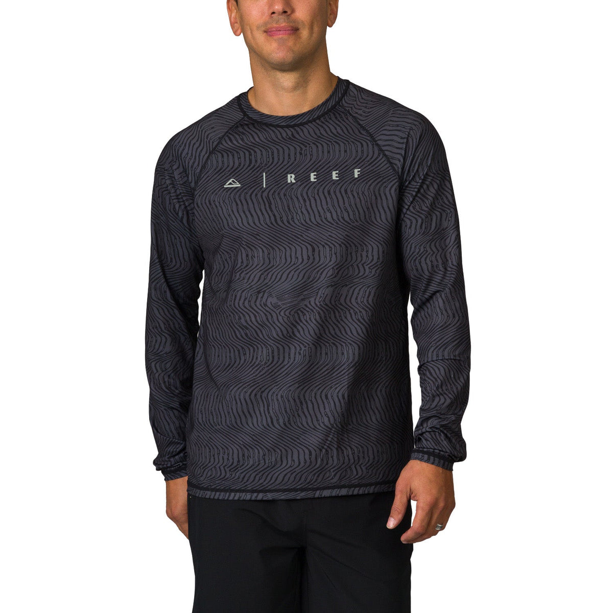 Man wearing a black wave-patterned Dune Performance Shirt facing front, highlighting comfort and surf-inspired design.
