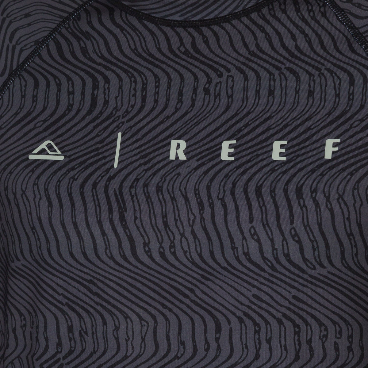 Close-up of the front chest area of the men's Dune Performance Shirt with a black wavy line pattern and REEF logo.