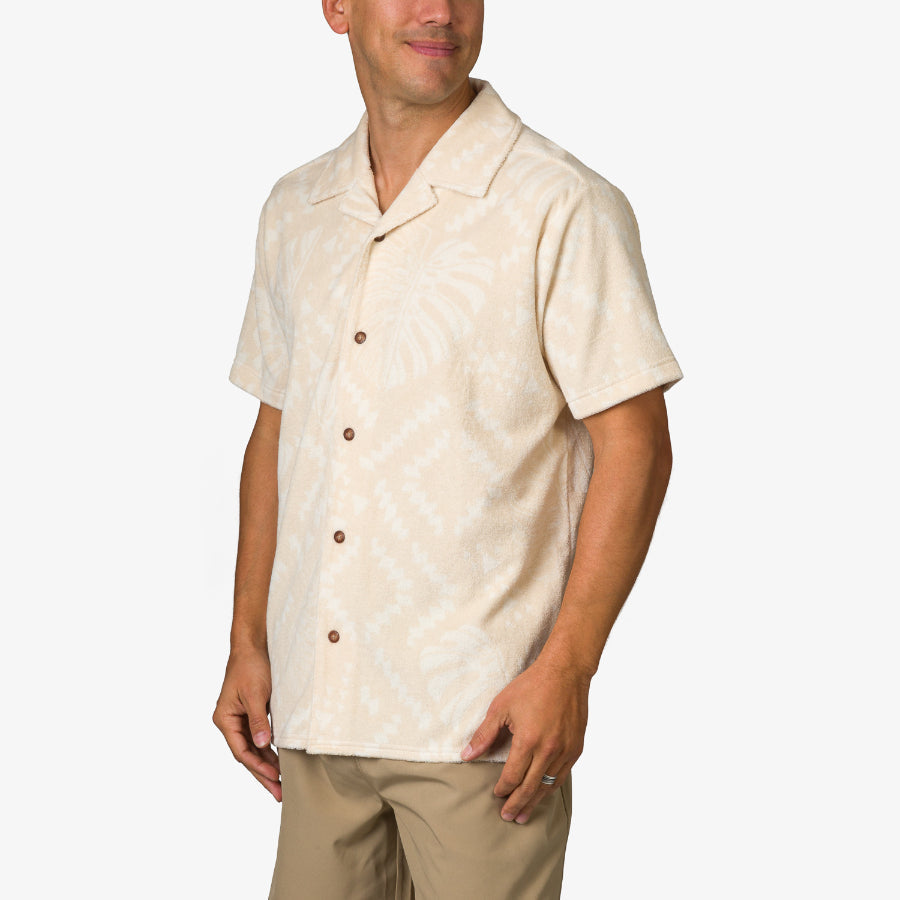 Men wearing a beige Novak Camp Shirt with a subtle tropical pattern, showcasing a relaxed, beach-inspired design.