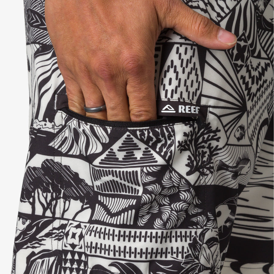 Close-up of a hand in the side pocket of the black and white patterned Marshall Boardshort for men, showing REEF tag.