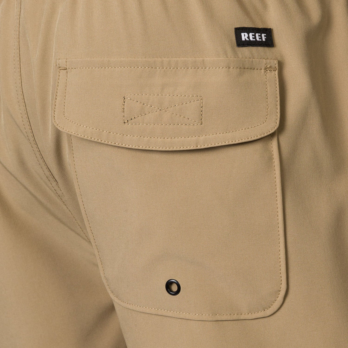 Close-up of the back pocket on the men's Garland Hybrid Short in tan, featuring durable stitching and REEF tag.