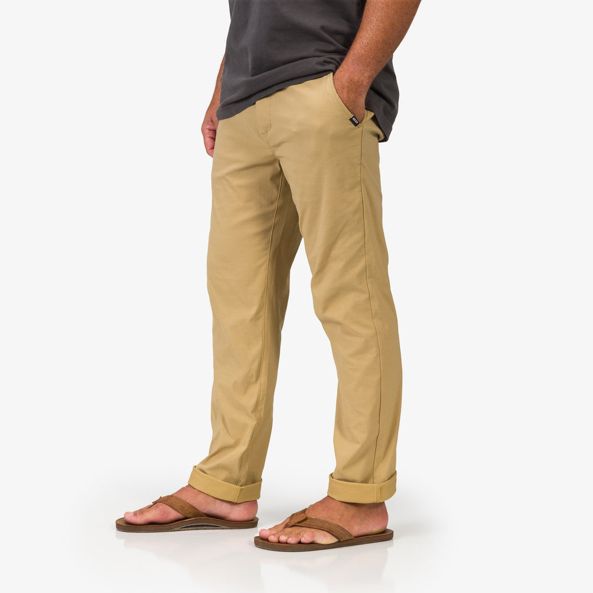 Men wearing Carrick Stretch Pant in khaki facing left, shown from mid-thigh down with sandals, beach-inspired comfort apparel.