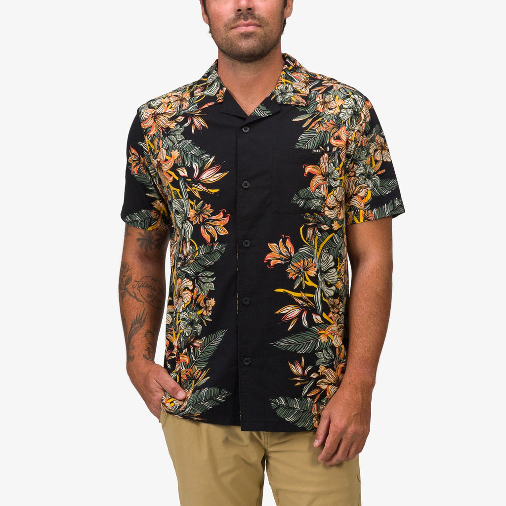 Front view of a man wearing the Drift Ss Camp Shirt with tropical floral patterns on black background, casual beach style