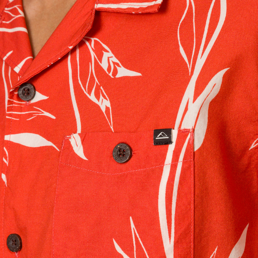 Close-up of the chest pocket and collar of the red Kaden Camp Shirt with white leaf print, showing button details.