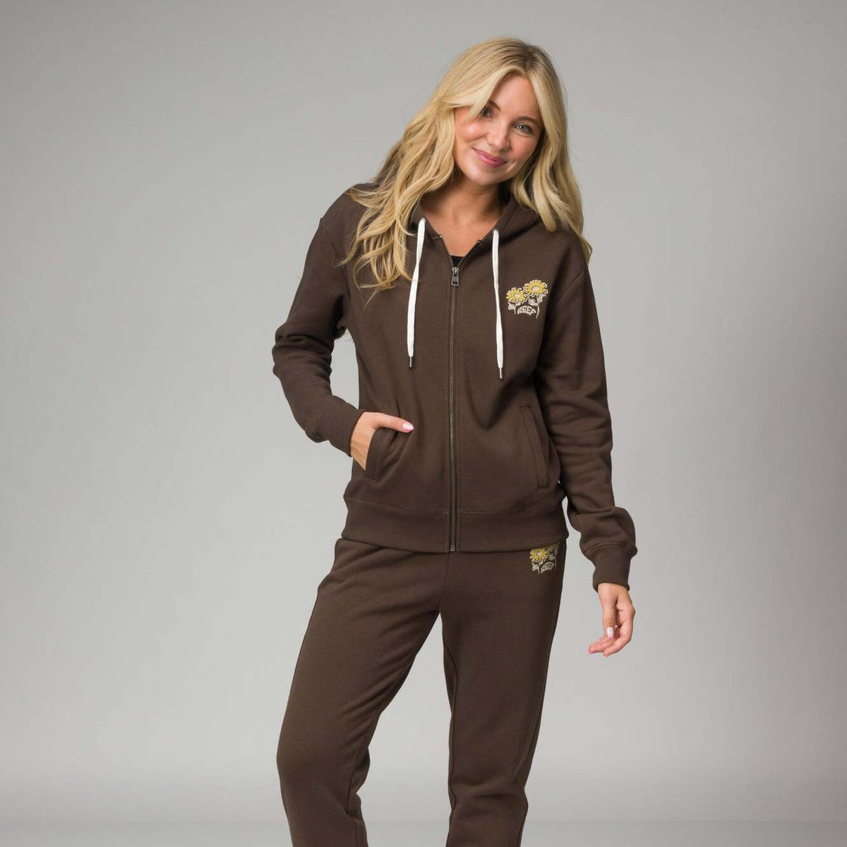 Woman wearing a front-facing brown Misty Fleece Full Zip hoodie with floral print, showcasing its soft, comfortable fabric.