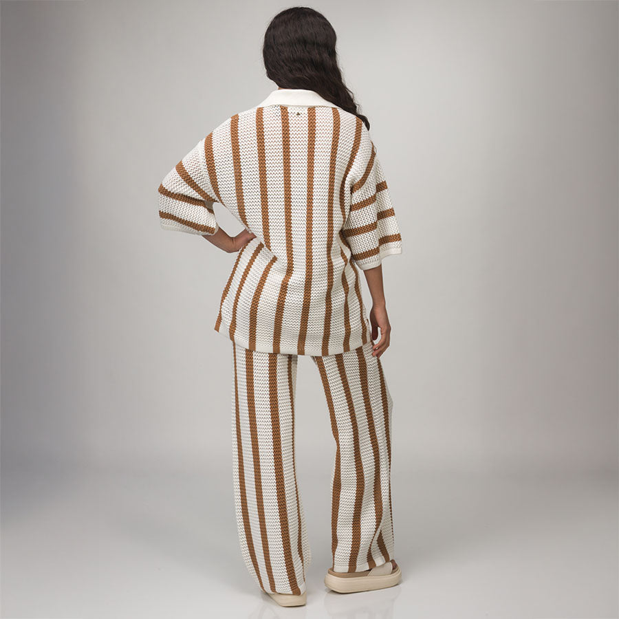 Woman wearing Mika Sweater Pant in white and brown stripes, standing with back facing camera, footwear facing sideways.