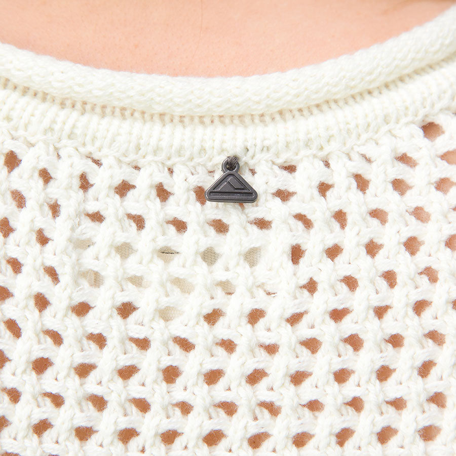 Close-up of Mika Sweater Tank knit fabric and neckline with metal branded pendant, showing texture and breathable design.