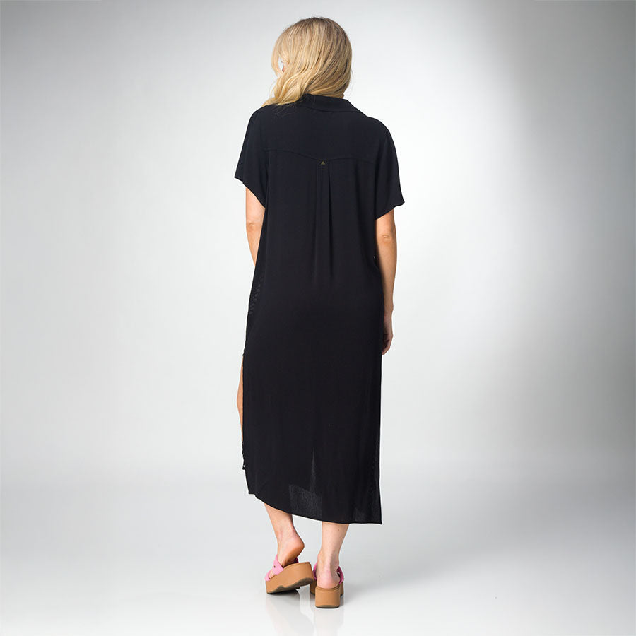 Woman wearing black Irina Shirt Dress facing away, paired with pink platform sandals facing backward, beach-inspired comfort style.