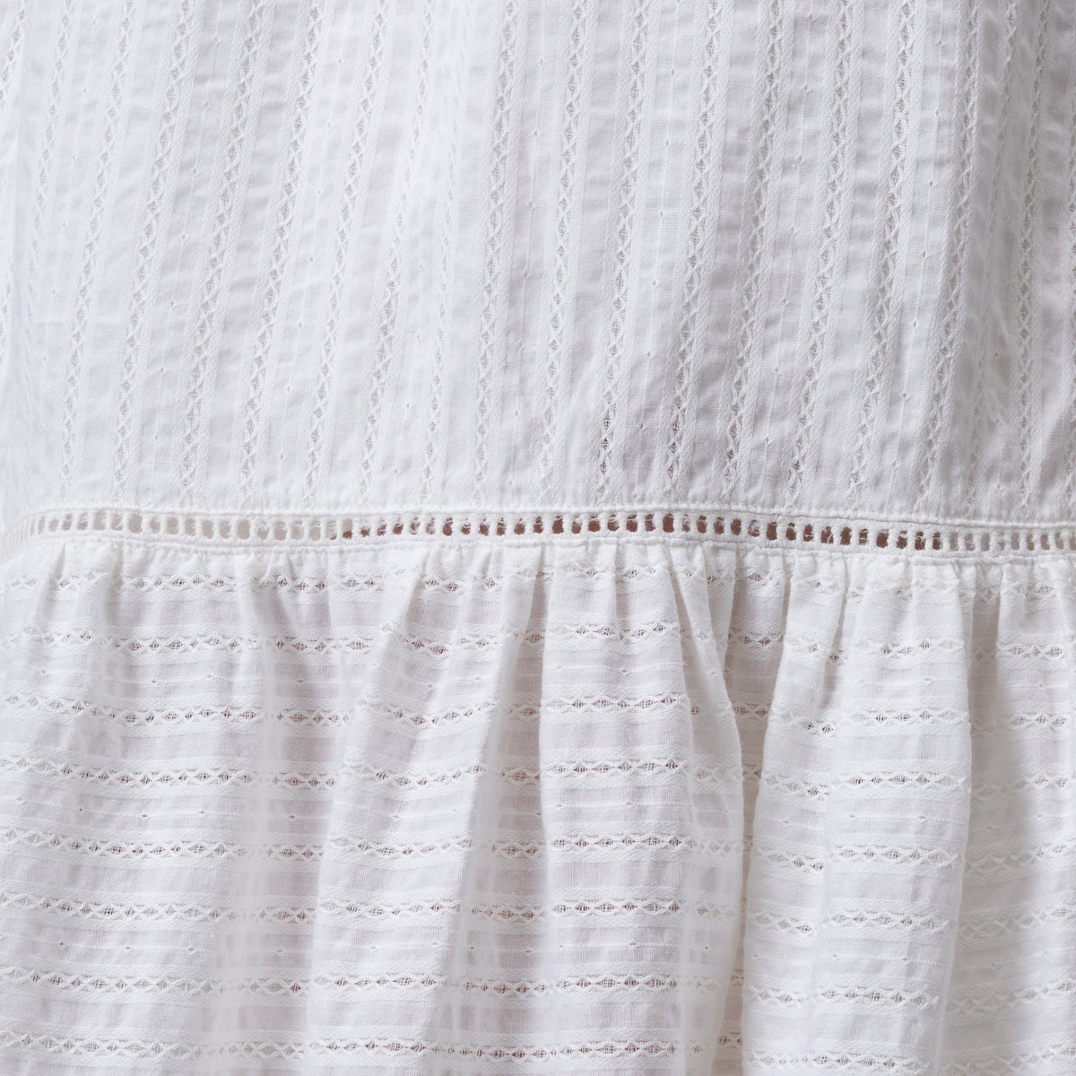 Close-up of white Yuni Maxi Dress fabric showing textured eyelet and delicate stitching details.