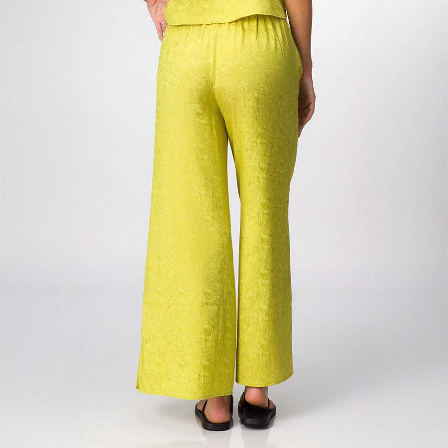 Ollie Pant in yellow green fabric with subtle pattern, shown from the back on a woman wearing black sandals, beach-inspired comfort