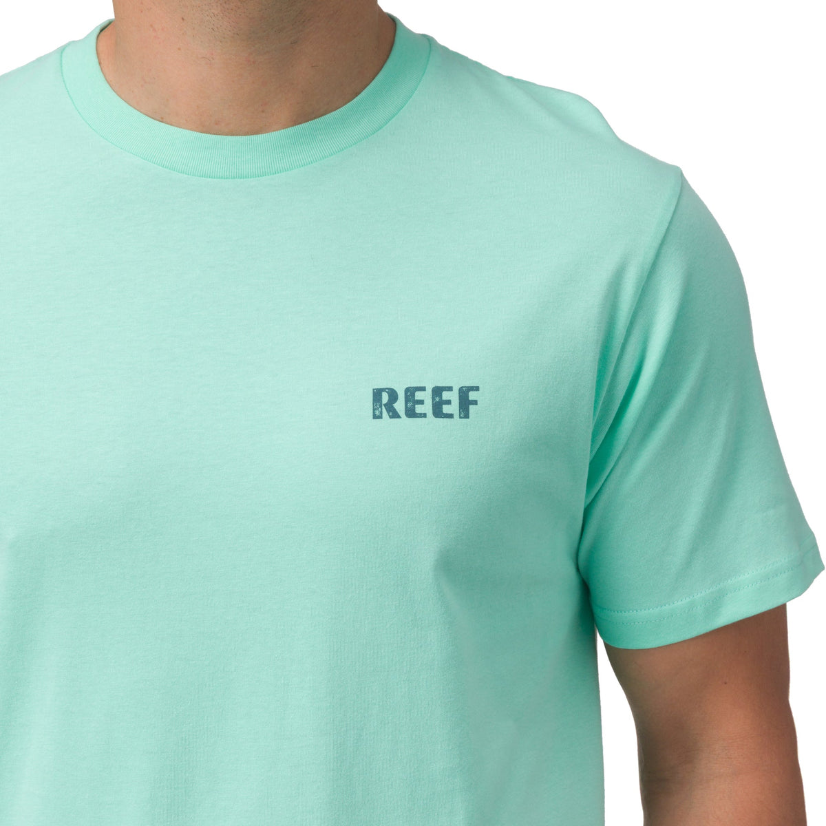 Close-up of the chest area of the Wellie Too Tee in soft aqua with REEF logo, offering beach-inspired comfort and style.