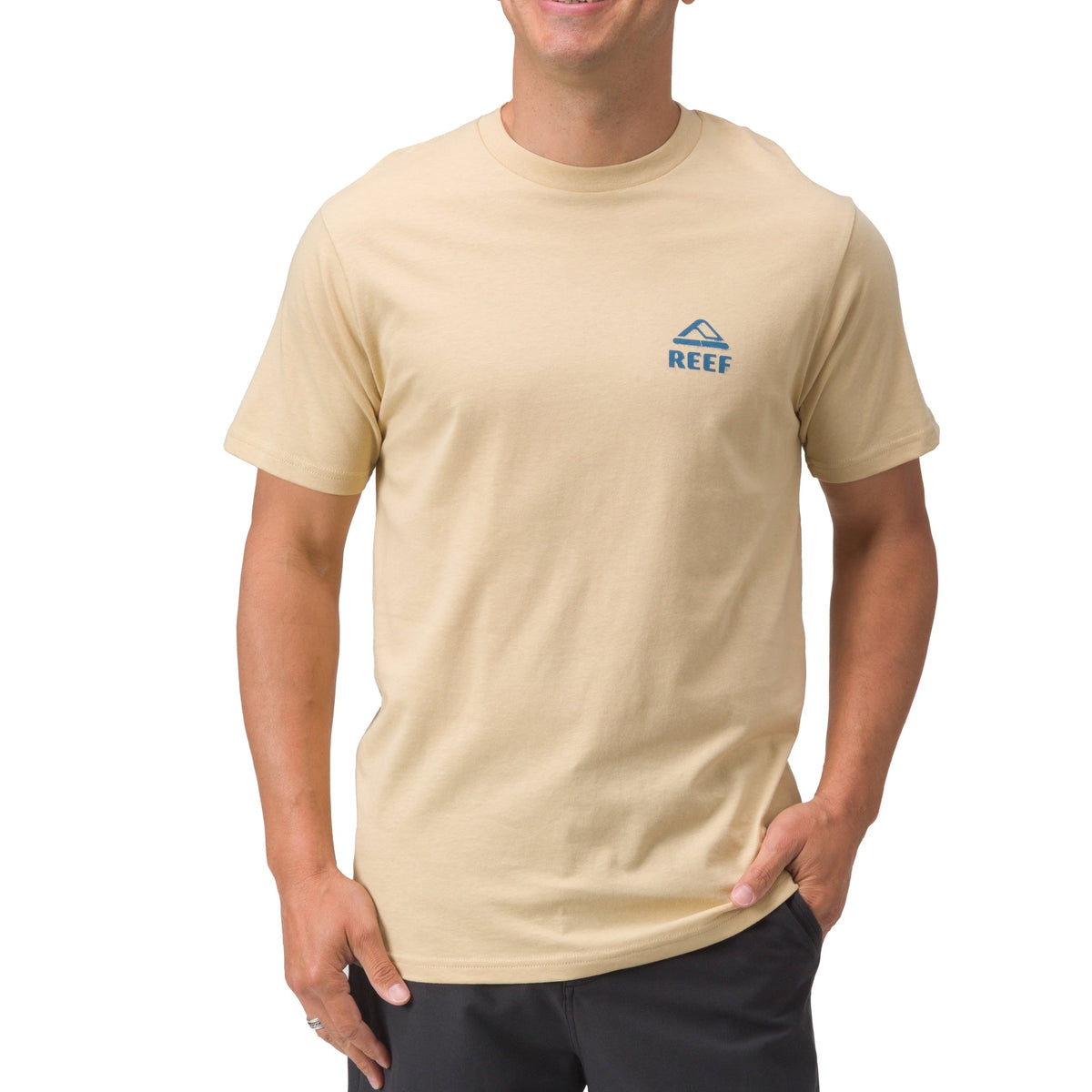 Front view of a man wearing a beige Xavier Tee with small blue REEF logo, beach-inspired comfort apparel for men.