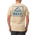 Man wearing beige Xavier Tee showing back with blue REEF logo, surf-inspired comfort apparel for men.
