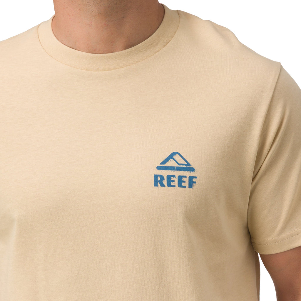 Close-up of the chest area of the Xavier Tee in beige with blue REEF logo, beach-inspired comfort apparel for men.