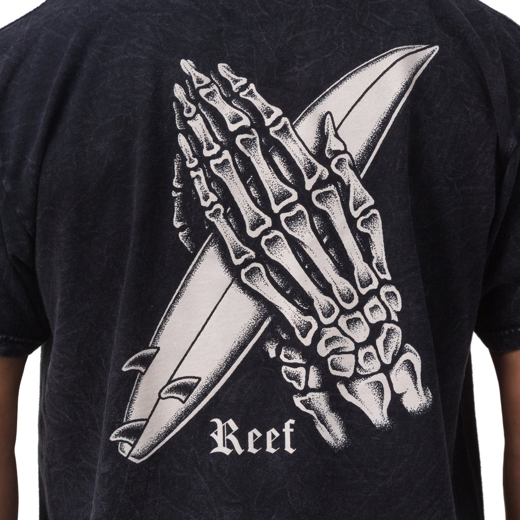 Close-up of the back of the Pray Tee showing a skeleton hand holding a surfboard print on black fabric.
