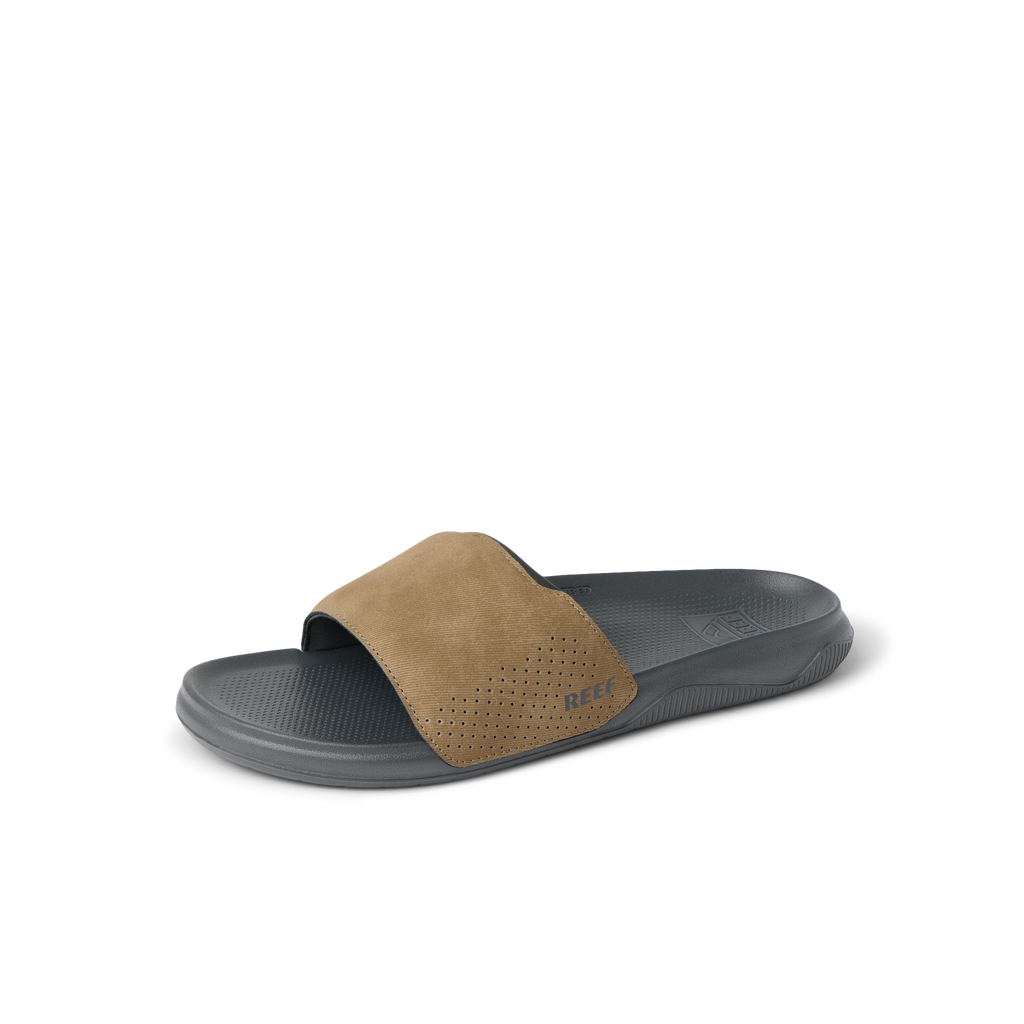 Tailslide slide sandal facing left, with tan perforated strap and grey cushioned footbed, designed for comfort and beach lifestyle.
