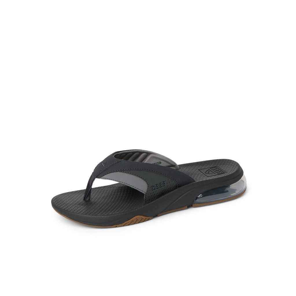 Fanning + men’s black and gum flip flop facing right, close-up of padded toe post and cushioned arch support.