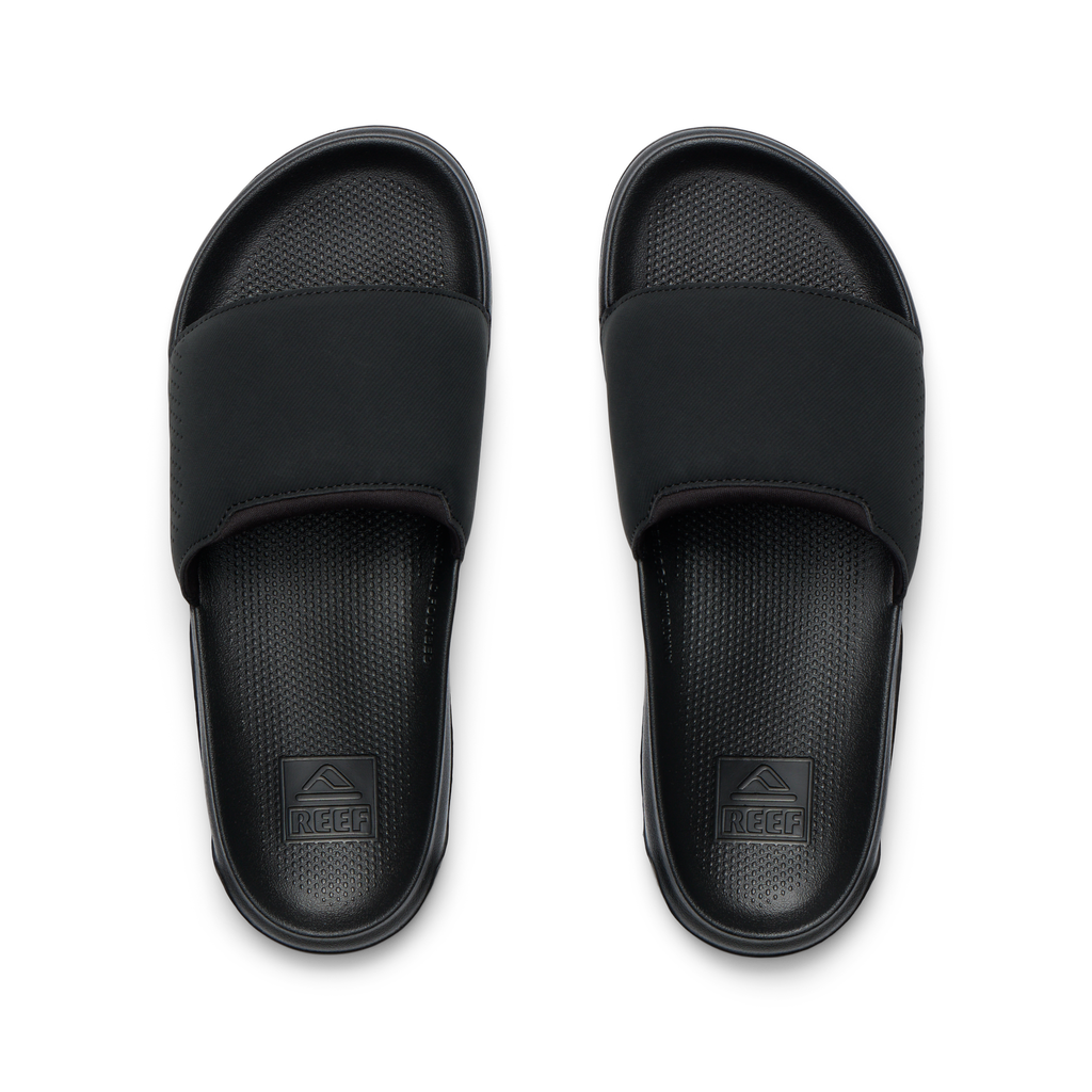 Tailslide men's black slides facing up, close-up of footbeds with textured cushioning and arch support for water-friendly comfort.