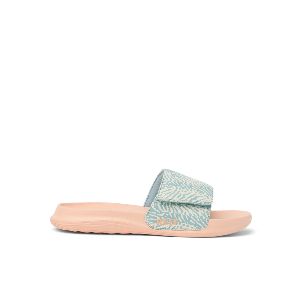 Kids Salty Slide left side view, blue haze strap with soft arch support and cushioned peach sole for beach comfort.
