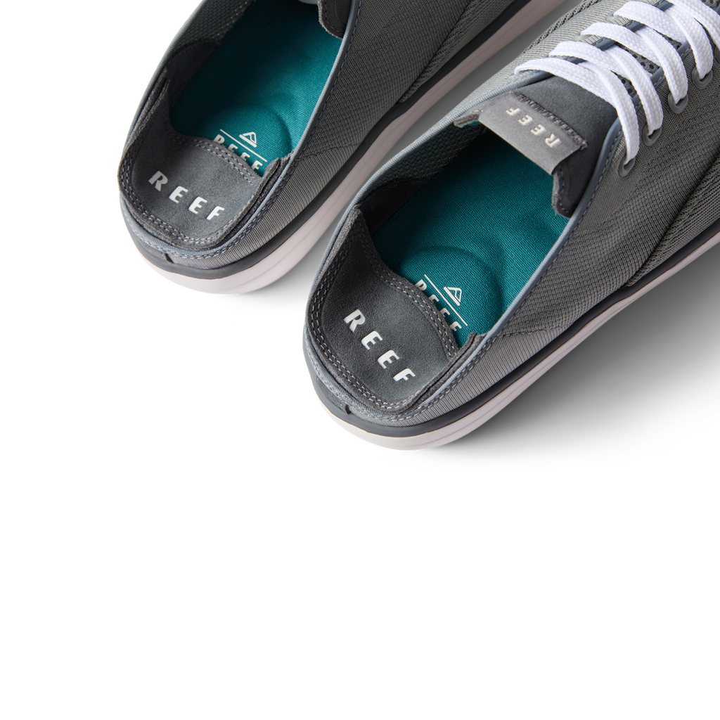 Top view close-up of Neptune Lido men's grey shoes facing upward, showing cushioned teal insoles and REEF branding.