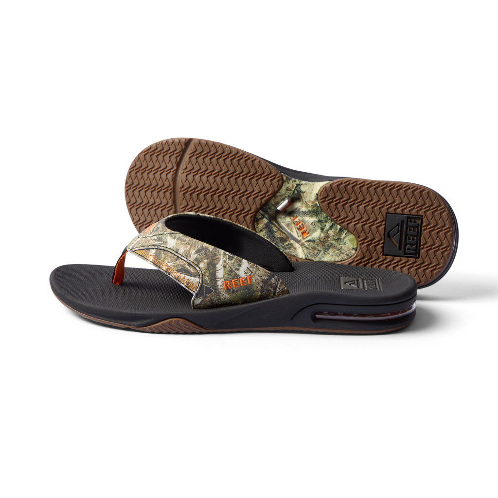 Fanning men's flip flop facing left, showing side and bottom with camo pattern, arch support, and cushioning