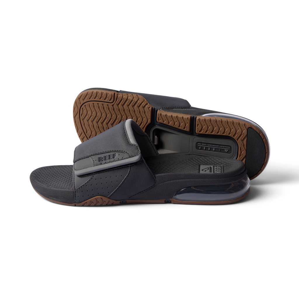 Pair of Fanning + Slide sandals facing left, black and grey with cushioned airbag heel, textured sole, water-friendly comfort design.