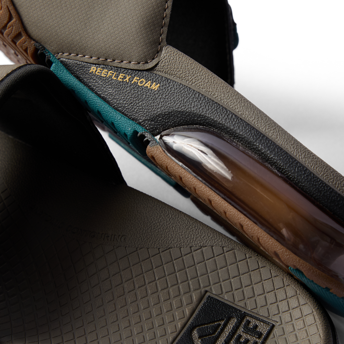 Close-up of tan and spruce slide midsole showing transparent REEFLEX foam cushioning and textured footbed details facing downward