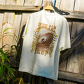 Back view of High-Stoke Relaxed Tee - Bone hanging outdoors showing surf-inspired graphic with beach lifestyle vibe