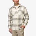Man wearing Houston Flannel Shirt in almond with plaid pattern, front view, hands in pockets, beach-inspired casual apparel.