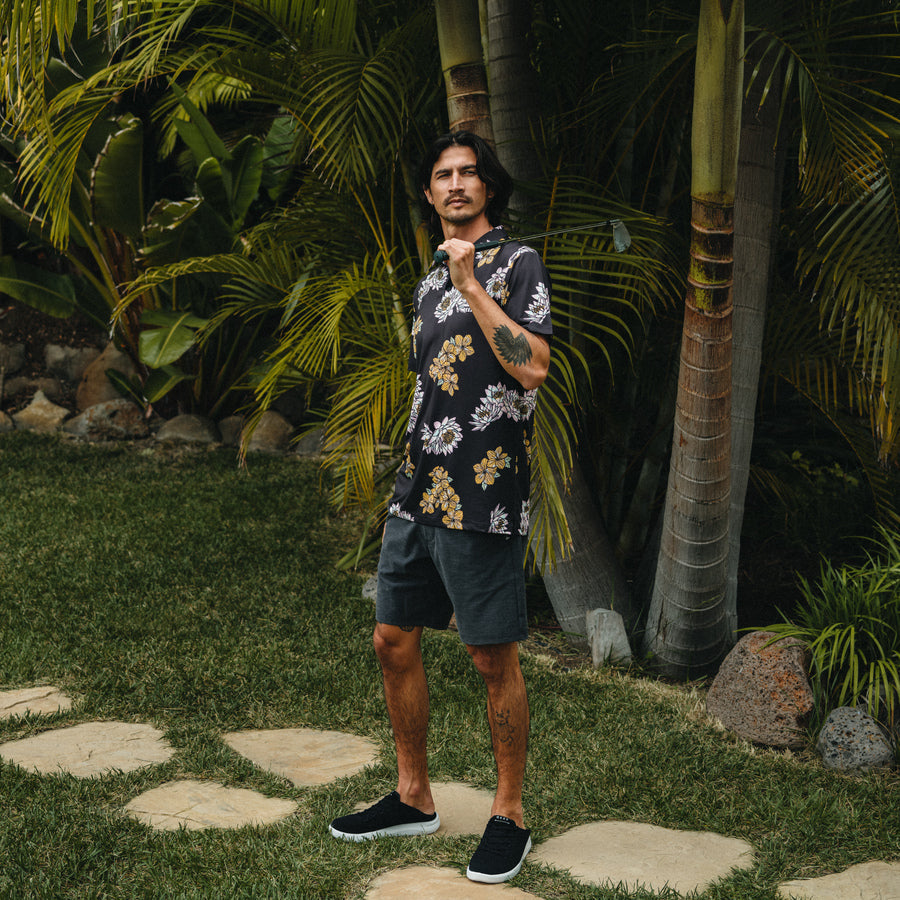Man wearing Wesland Polo facing forward in tropical garden, showcasing beach-inspired casual men's apparel.