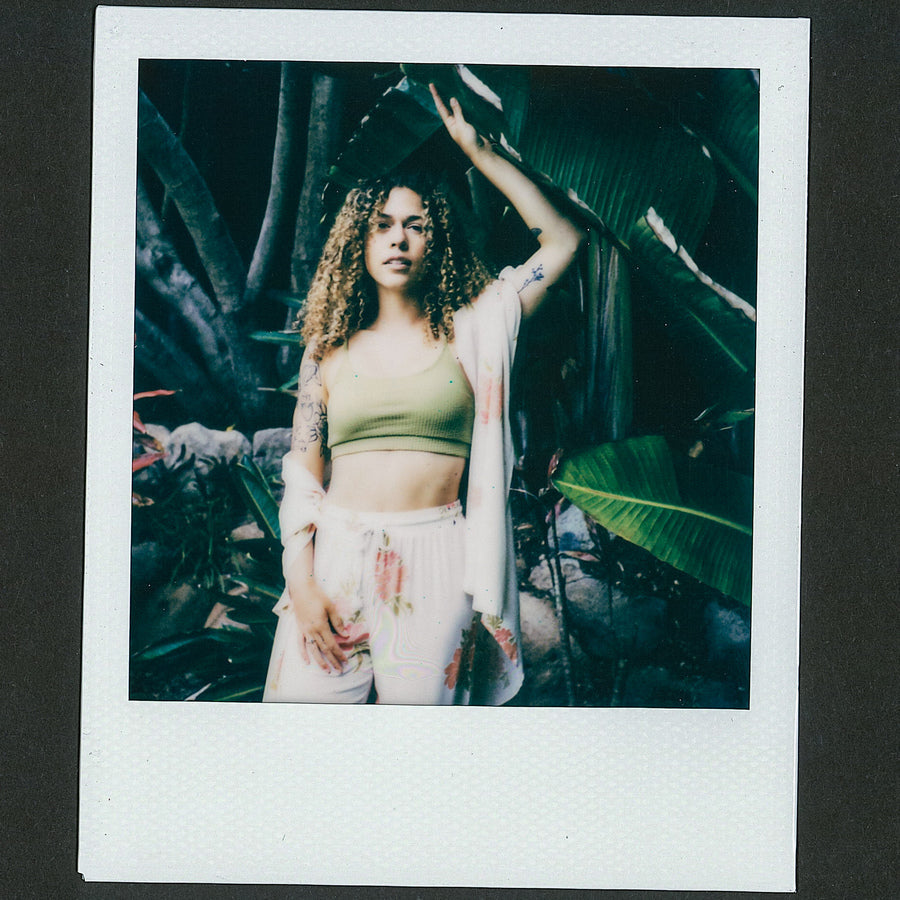 Woman wearing Belladona Pant with floral pattern standing in tropical setting, showcasing relaxed, beach-inspired comfort style