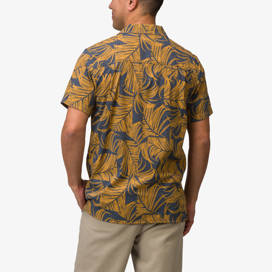 Back view of men's Kantis Shirt in buckthorn brown with blue tropical leaf print, showcasing comfort and surf-inspired style.