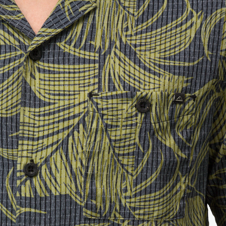 Close-up of the chest pocket on the Kantis Shirt, featuring green leaf pattern on textured dark fabric, surf-inspired comfort apparel.