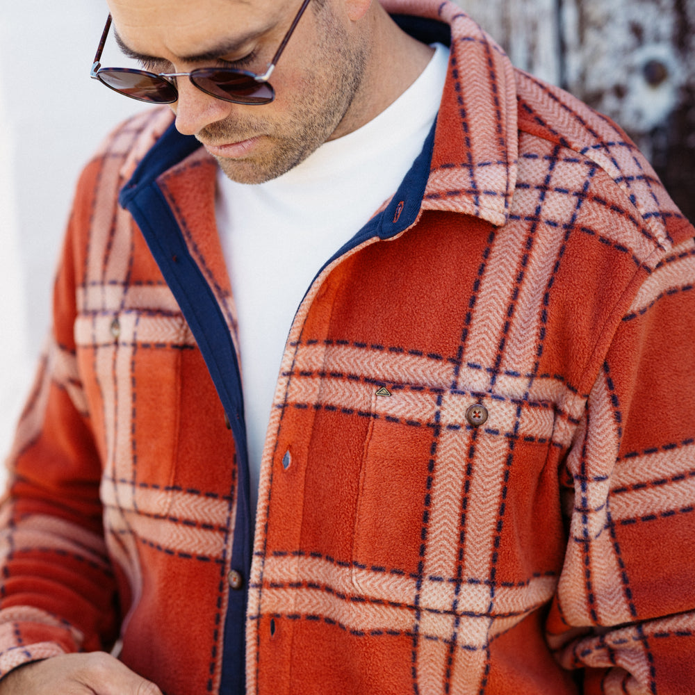 Man wearing a rust-colored Karter Shirt Jacket with plaid pattern, showing front upper torso and collar details.