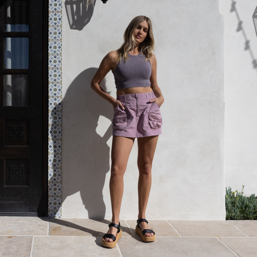 Woman wearing Vista Higher Raya sandals facing forward, styled with casual summer shorts and sleeveless top, beach-inspired comfort.