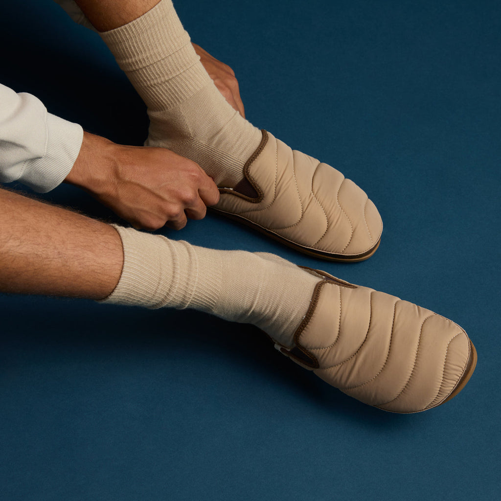 Men's Cushion Homey slip-on footwear in acorn color shown from left side, highlighting quilted upper and comfort design.