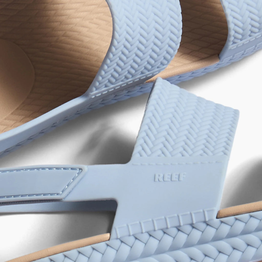 Close-up of the side and straps of light blue Reef Water Vista sandals facing left, featuring molded footbeds.
