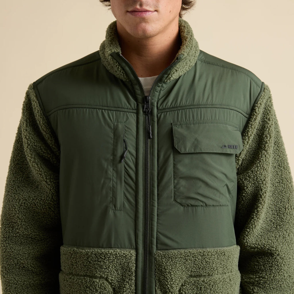 Front view of a person wearing an olive green Cooke Sherpa Jacket with padded chest panels and soft fleece sleeves.