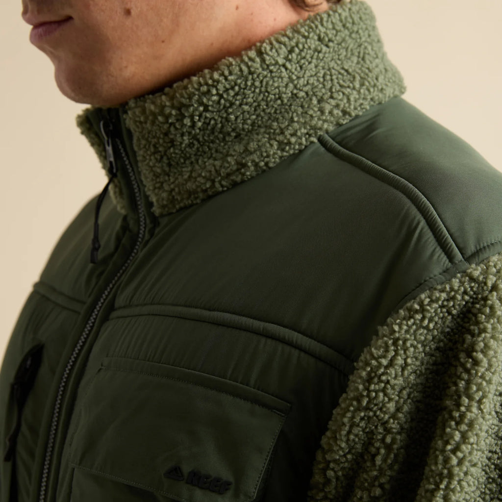 Close-up of the upper left side of the Cooke Sherpa Jacket showing olive green sherpa collar and fabric with chest pocket detail