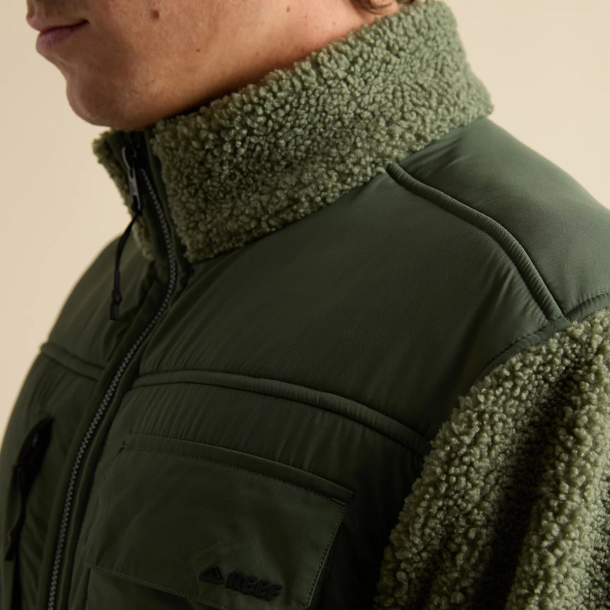 Close-up of the upper left side of the Cooke Sherpa Jacket showing olive green sherpa collar and fabric with chest pocket detail