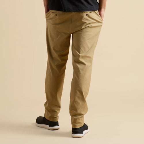 Rear view of men’s Carrick Stretch Pant in tan, paired with black shoes facing away, highlighting comfort and casual style.