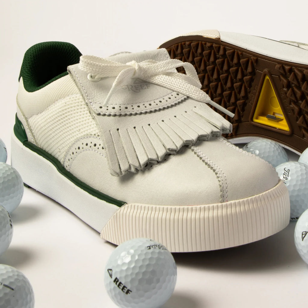 Onshore Pebble men's sneaker facing left, close-up of toe and fringe detail with golf balls on white surface.