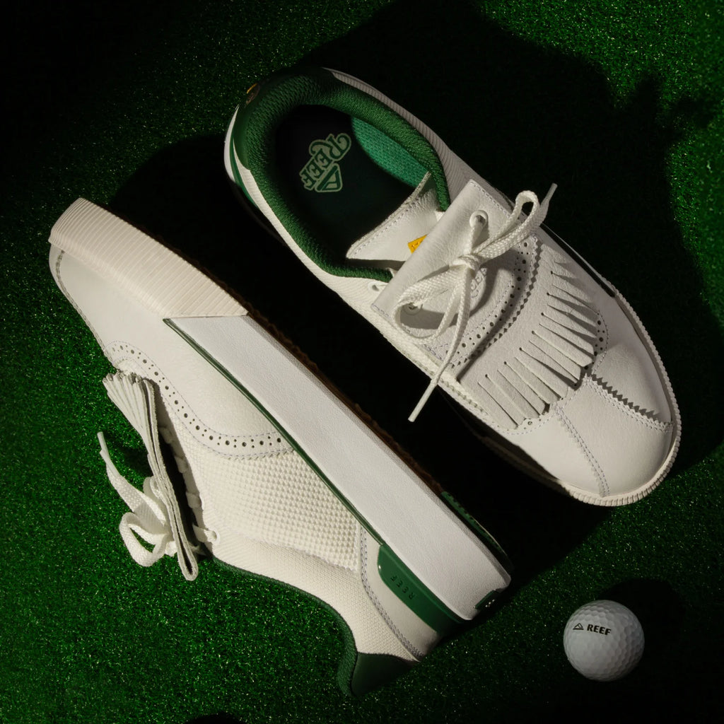 Top and side view of white and green Onshore Pebble men's shoes on green turf with a REEF golf ball nearby