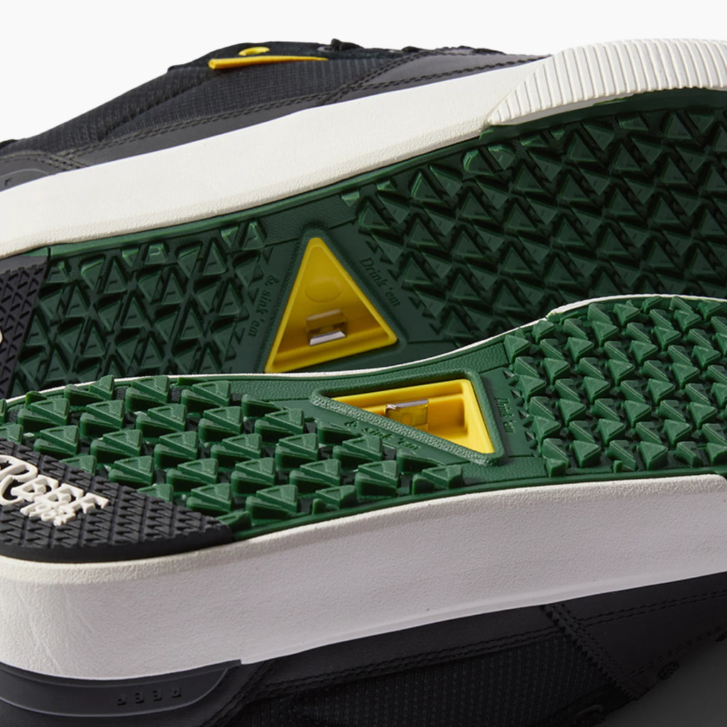 Onshore Pines men’s shoe soles facing up, showing textured green and black rubber with yellow accents for grip and comfort.