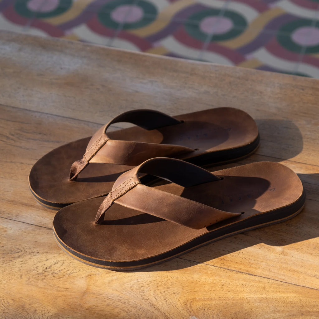 Ojai Classic men's brown flip flops facing right with soft-rebound cushioning and anatomical arch support on wooden surface.