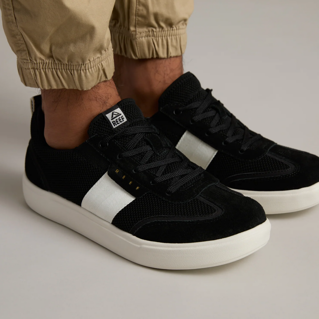 Triton men's black sneaker facing right with white sole and side stripe, showing front and side comfort design details.