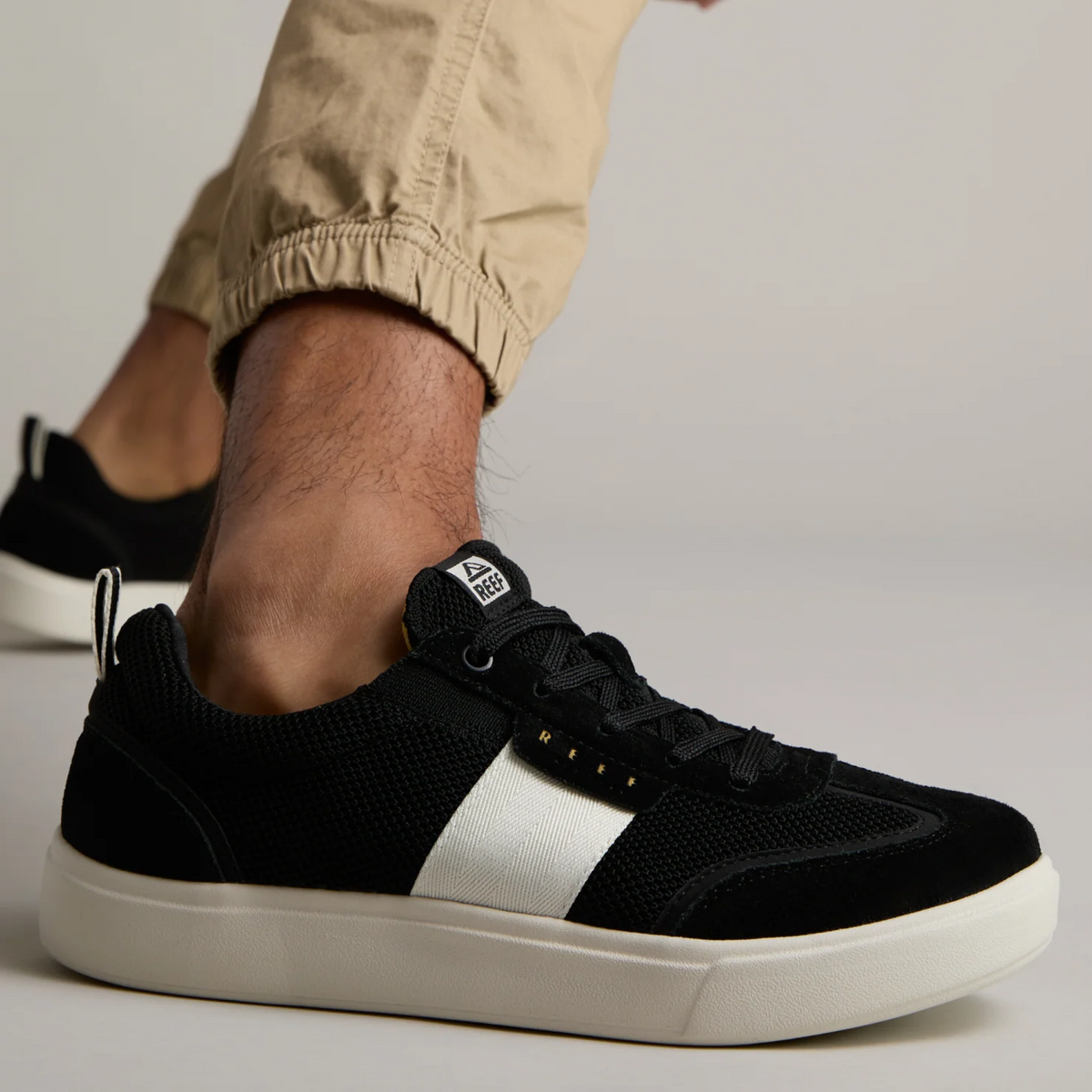 Black and white Triton sneaker facing right, side view showing soft cushioning and anatomical arch support on foot.