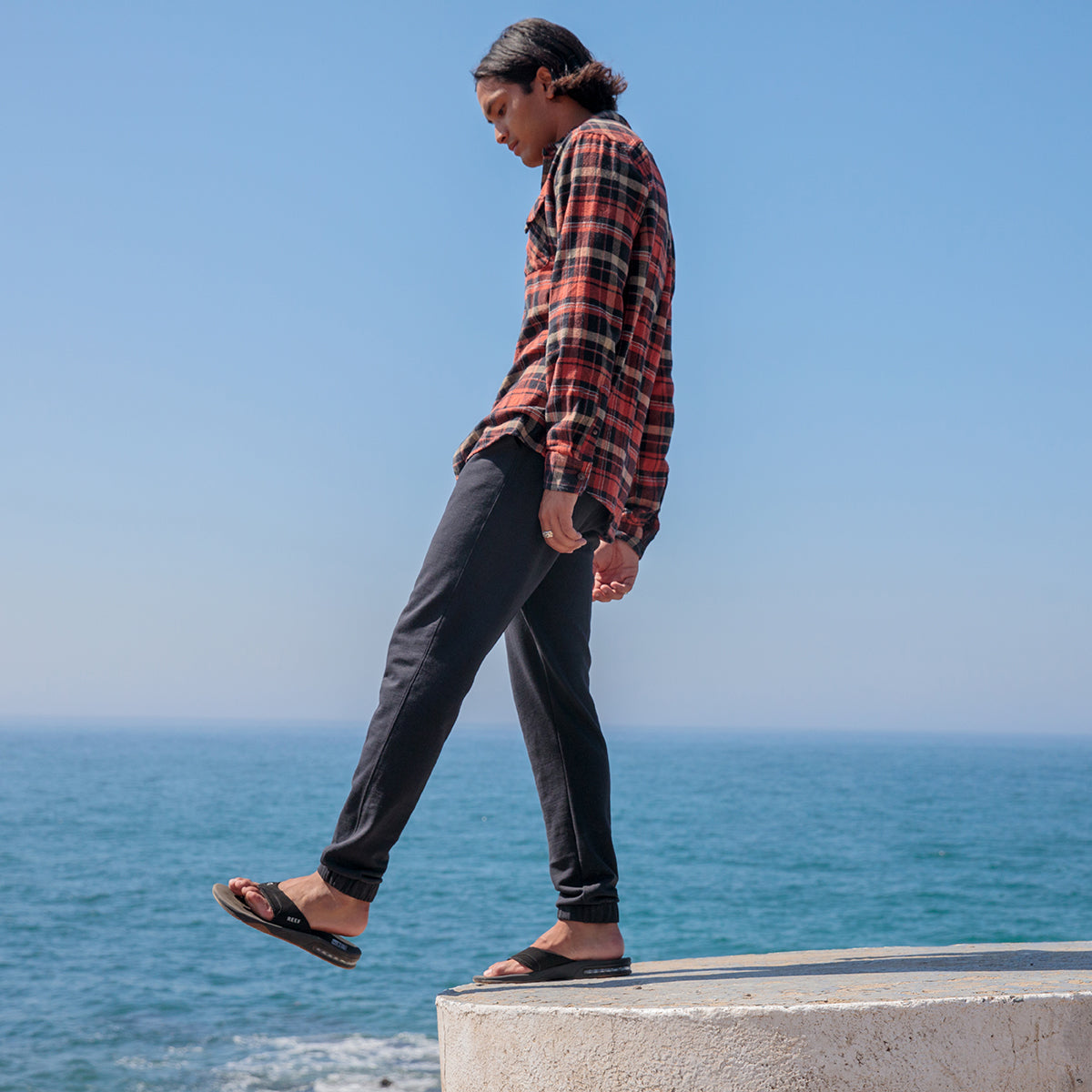 Side view of men's Fanning sandals being worn, showing soft-rebound cushioning and anatomical arch support by the ocean.
